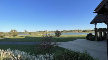 A view of a golf course with a clear sky, a body of water, and a gazebo structure.