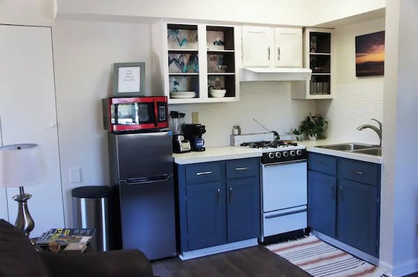 A compact kitchen with a microwave, stove, and cabinets.