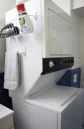 A front-loading washing machine with a detergent dispenser and a towel hanging nearby.