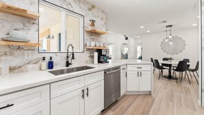 A modern kitchen with white cabinets, a marble backsplash, and a built-in dishwasher. - ❤NEW 15% DISCOUNT❤Stock Tank Pool❤Hot Tub❤Hammocks (Joshua Tree)