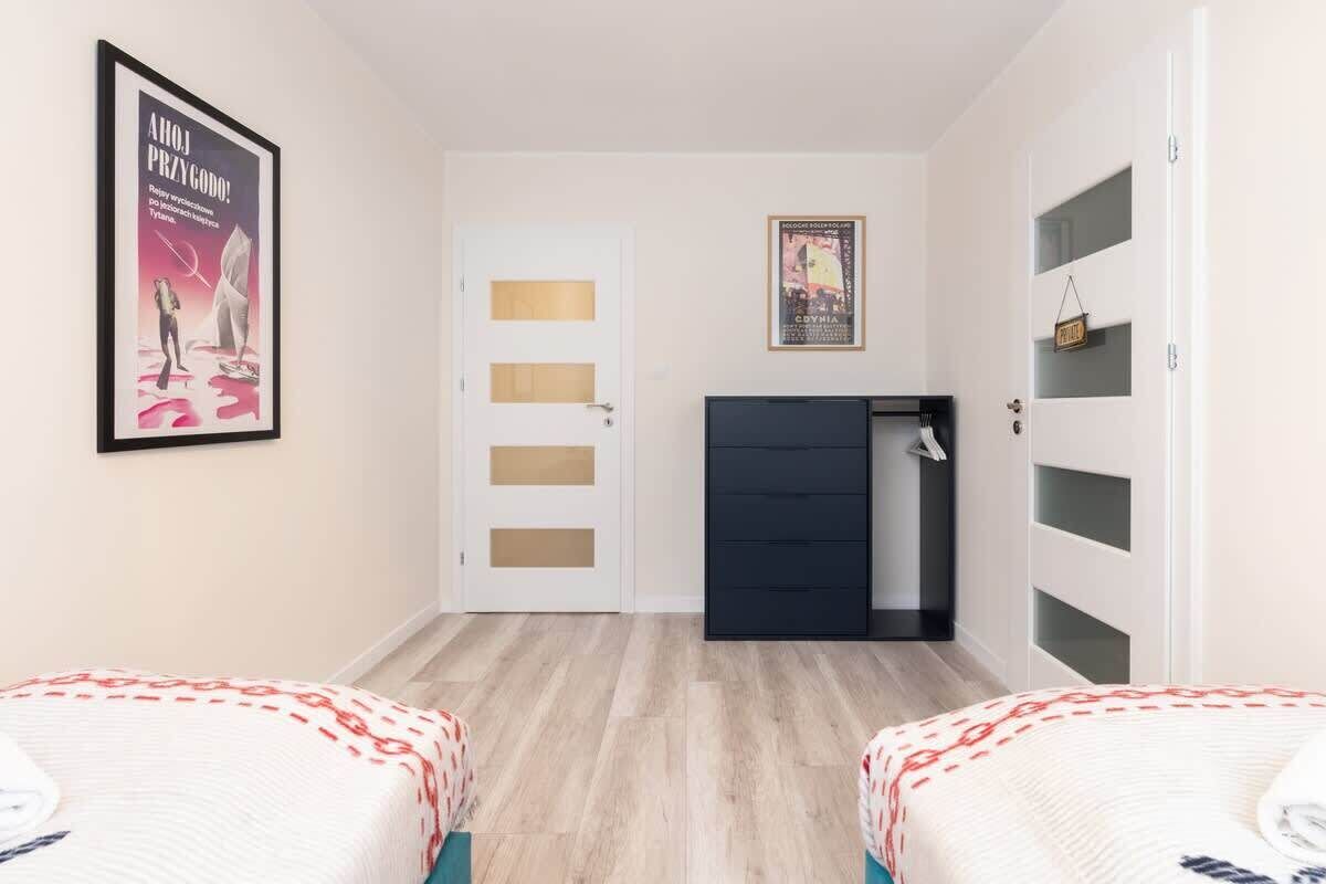 Een slaapkamer met twee bedden, een garderobe, een deur met geëtste glaspanelen en een poster aan de muur.