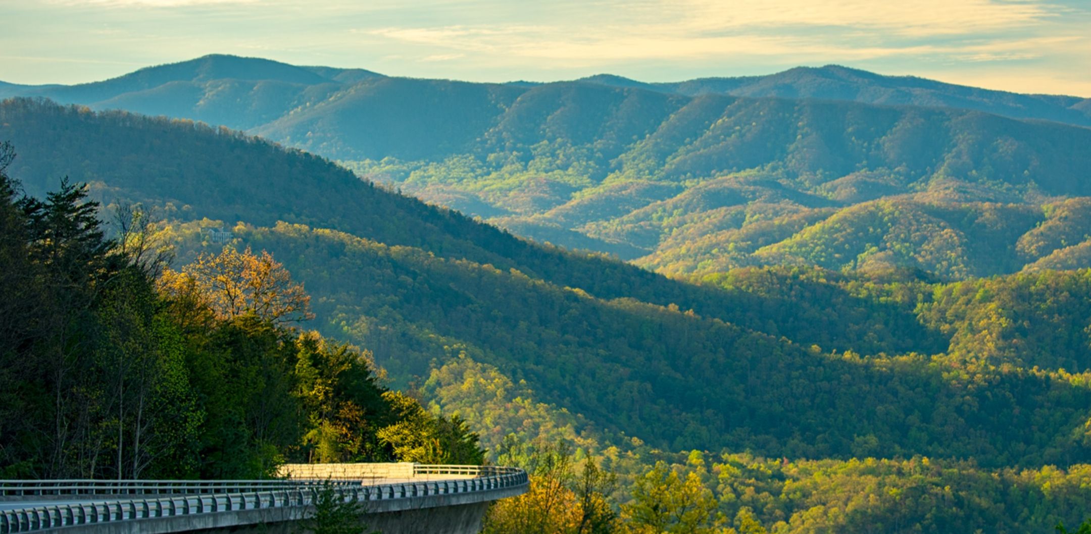 A bridge with a view of forested mountains.
