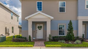 A two-story residential building with a front entrance, a mailbox, and a wreath on the door. - Brand New, Stylish 4-Bed 3-Bath Home. Conservation Views & Gated Resort Amenities. Near Disney! (Davenport)