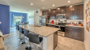 A modern kitchen with granite countertops, stainless steel appliances, and dark wooden cabinets. - Brand New, Stylish 4-Bed 3-Bath Home. Conservation Views & Gated Resort Amenities. Near Disney! (Davenport)