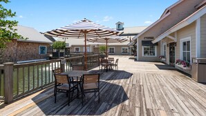 A wooden deck with outdoor seating and umbrellas, a pool, and a building with a sign reading "Sea Breeze." - A · New 4Br King Beds Steps to Beach &2nd Pier #A (Myrtle Beach)