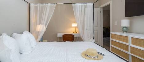 A hotel room with a bed, a desk, a chair, a bedside table with a lamp, a wardrobe, and a TV mounted on the wall.