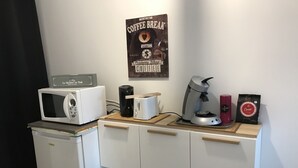 Eine Küchenzeile mit Mikrowelle, Kaffeemaschine, Toaster und Mülleimer.