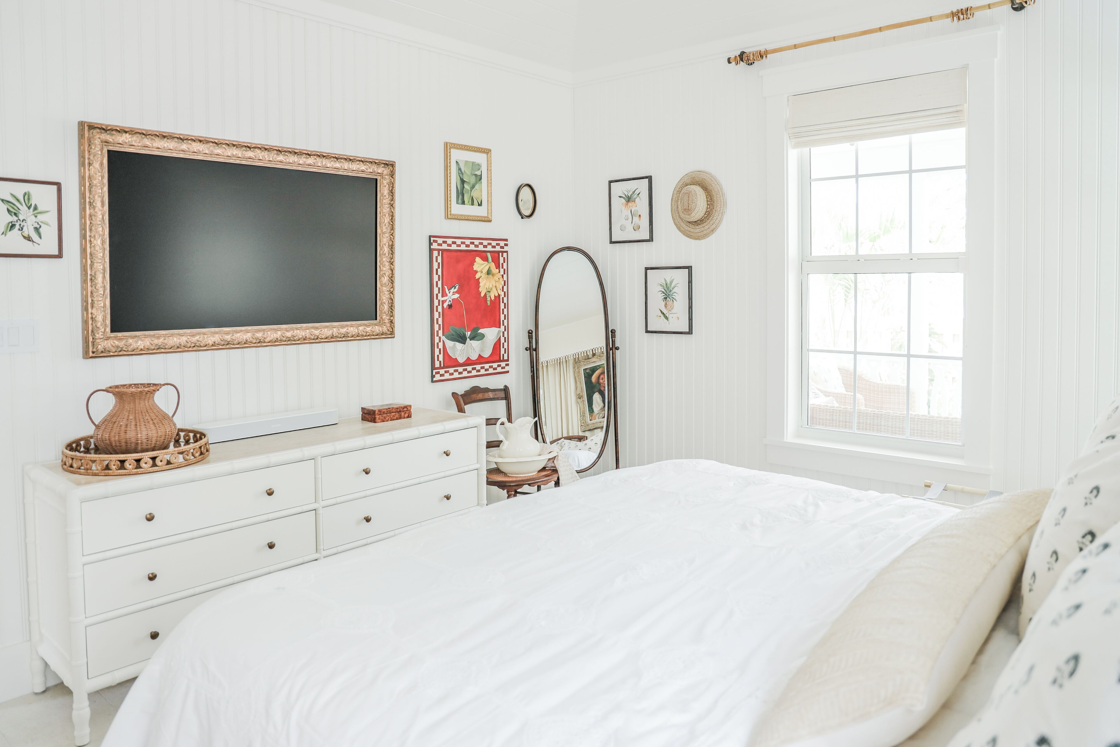 A bedroom with a bed, dresser, mirror, and wall art.