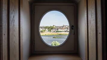 A room with a circular window offering a view of a river and buildings.