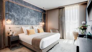 Una habitación de hotel moderna con una cama grande, mesitas de noche, un escritorio y vistas al exterior.