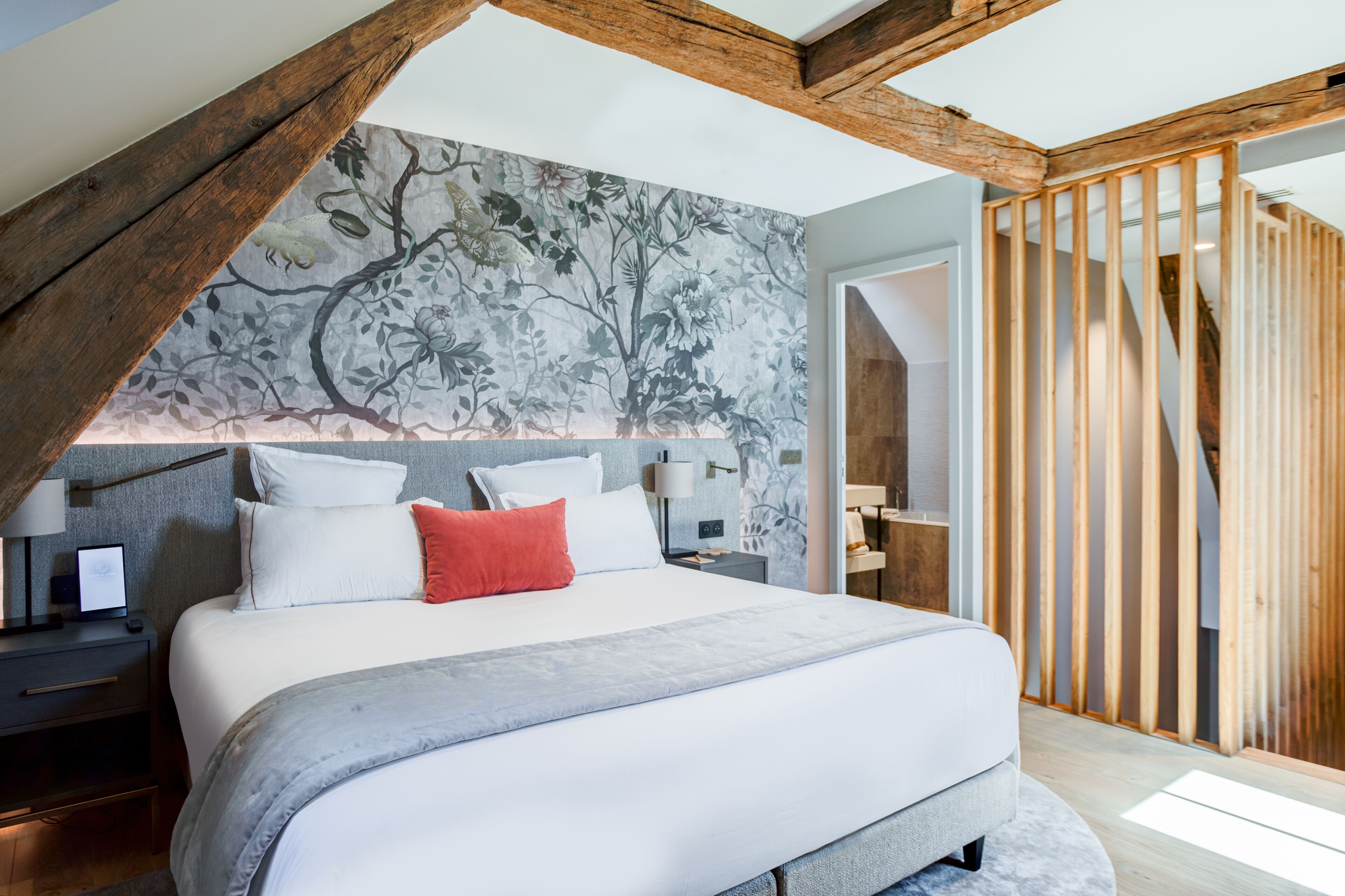 Un dormitorio moderno con una cama grande, vigas de madera y un papel tapiz floral.
