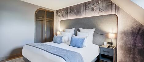 A modern bedroom with a large bed, a nightstand, and a headboard with a textured wall behind it.
