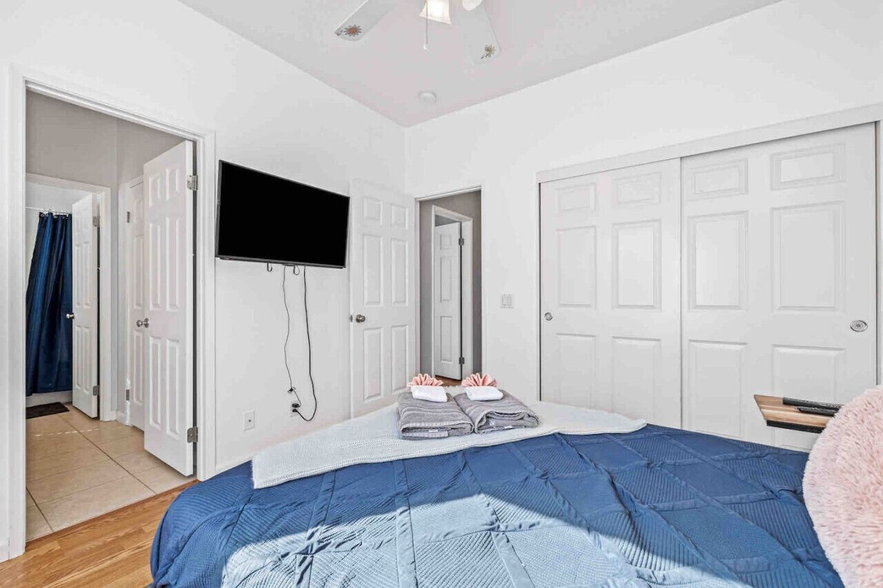 Ein Schlafzimmer mit einem Bett, einem an der Wand befestigten Fernseher und weißen Türen.