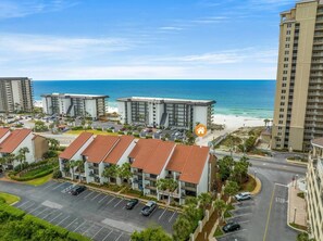 Un hôtel situé sur la côte, composé de plusieurs bâtiments, doté d’un parking et offrant une vue sur la plage.