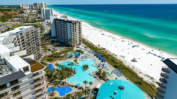 Ein Resort mit großzügiger Poolanlage, einem Strand und Hochhäusern.
