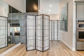 Une cuisine moderne dotée d’un four encastré et d’une cloison en verre ornée de motifs végétaux.