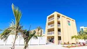Un hotel a più piani con balconi, palme e un cielo azzurro.