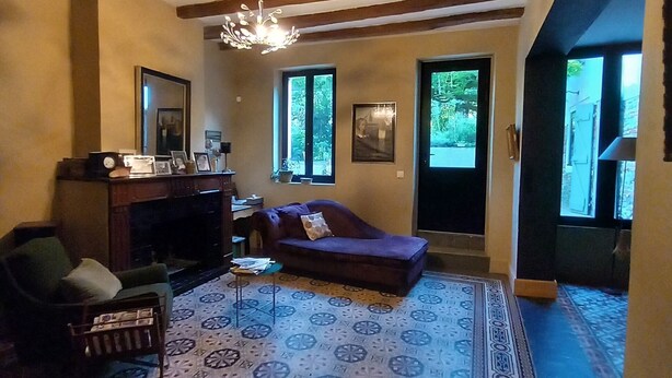 A living room with a patterned floor, a sofa, a chair, a fireplace, and a chandelier.