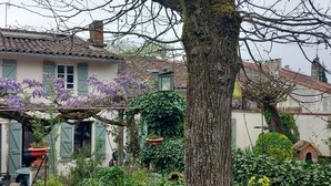 A traditional house with a tiled roof, green shutters, and purple flowering vines.