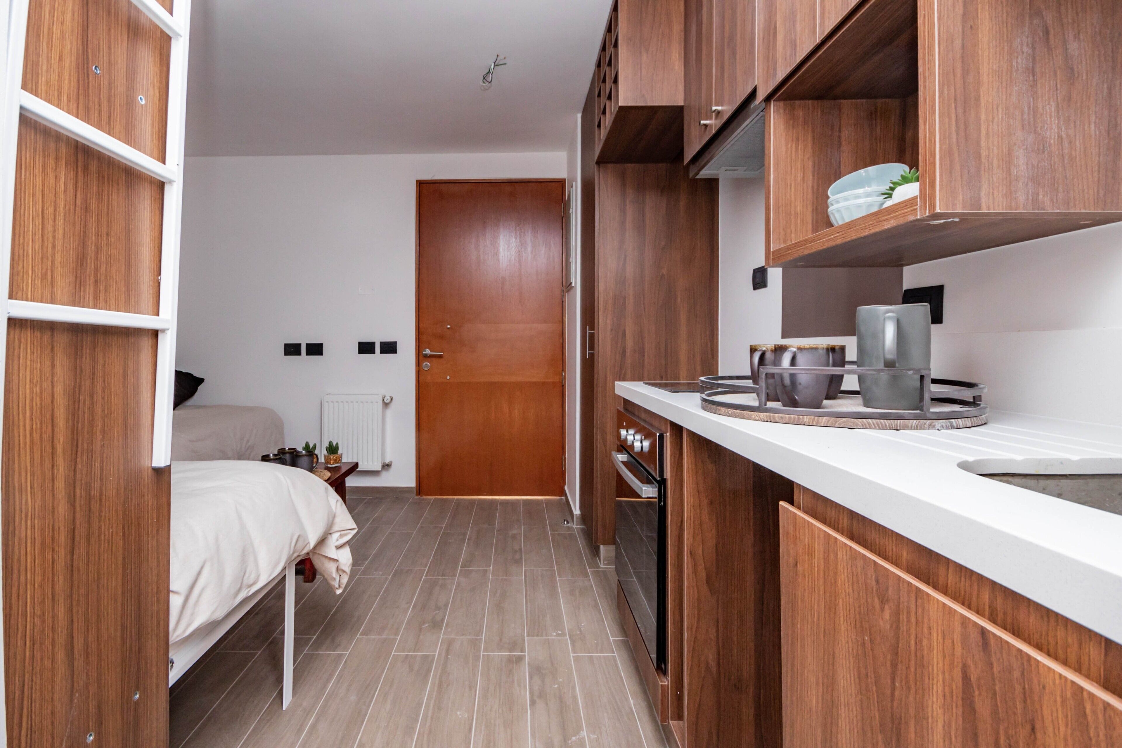 A compact kitchen with wooden cabinets, a white countertop, and a small sink.