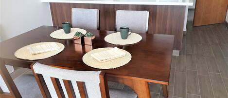 A dining area with a wooden table, four chairs, and placemats.