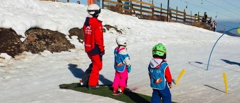 Pista de esquí nevada con vallas de madera y un telesilla al fondo.