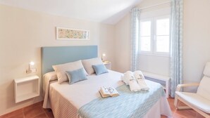 A neatly arranged bedroom with a bed, bedside tables, a chair, and a window with curtains. - Casa Sierra Alhaurín de la Torre by Ruralidays (Málaga)