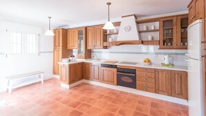 A kitchen with wooden cabinets, a built-in oven, and a white countertop. - Casa Sierra Alhaurín de la Torre by Ruralidays (Málaga)