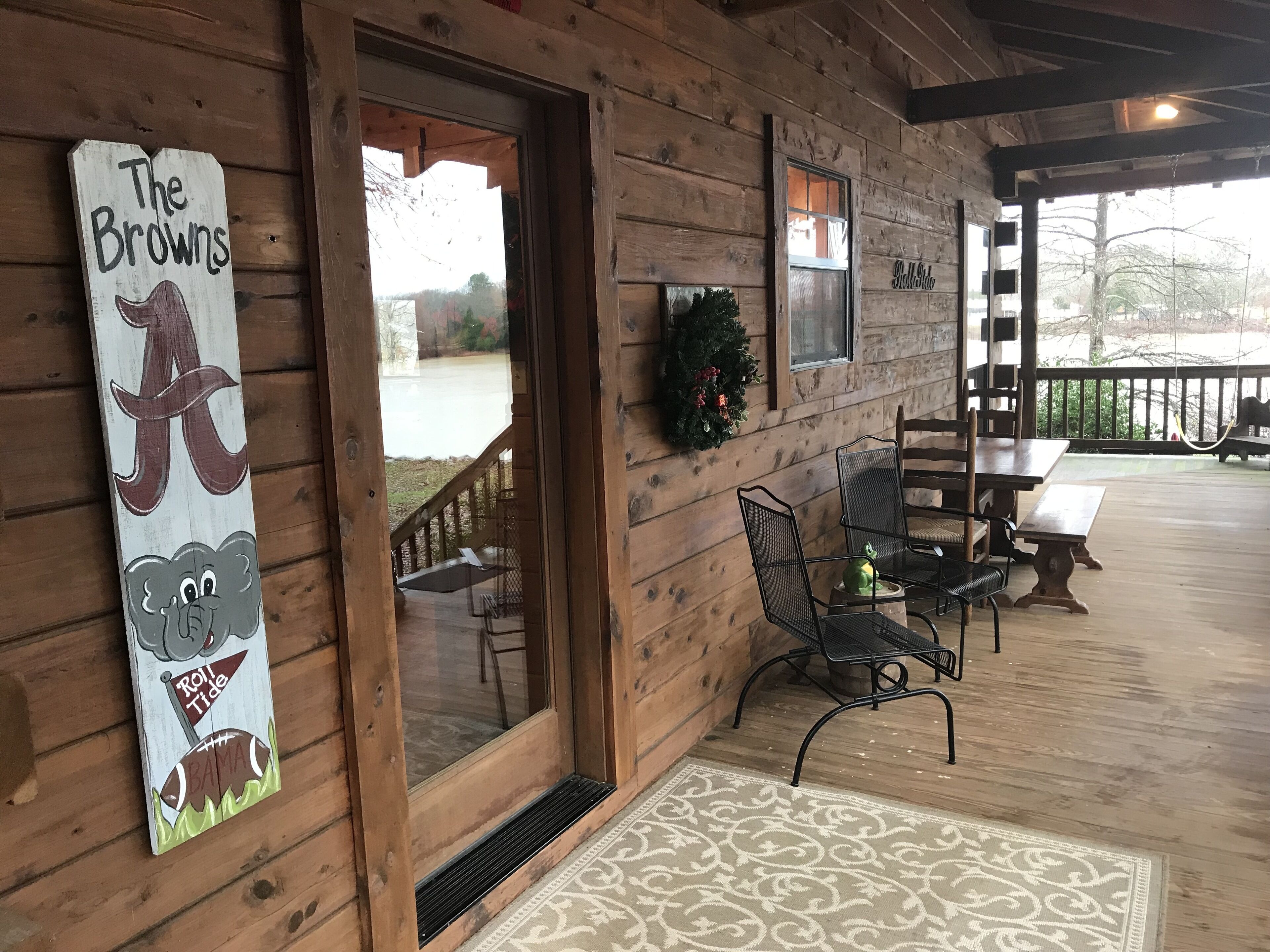 A wooden cabin with a sign reading "The Browns," a porch with outdoor seating, and a view of a snowy landscape.