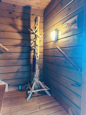 Ein Holzblockhaus-Innenraum mit einem an der Wand aufgehängten Hirschgeweih, einem Willkommensschild und einer Leuchte.