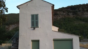 Ein zweistöckiges Gebäude mit einer Treppe links, einer Garagentür rechts und einem Kind, das mit einem Spielzeugauto darauf herumspielt.