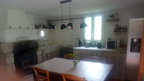 Eine Küche mit Esstisch, Stühlen, Herd, Mikrowelle und Pendelleuchten.