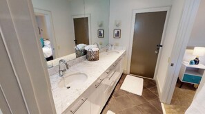 A modern bathroom with a double sink, a large mirror, and a walk-in shower.