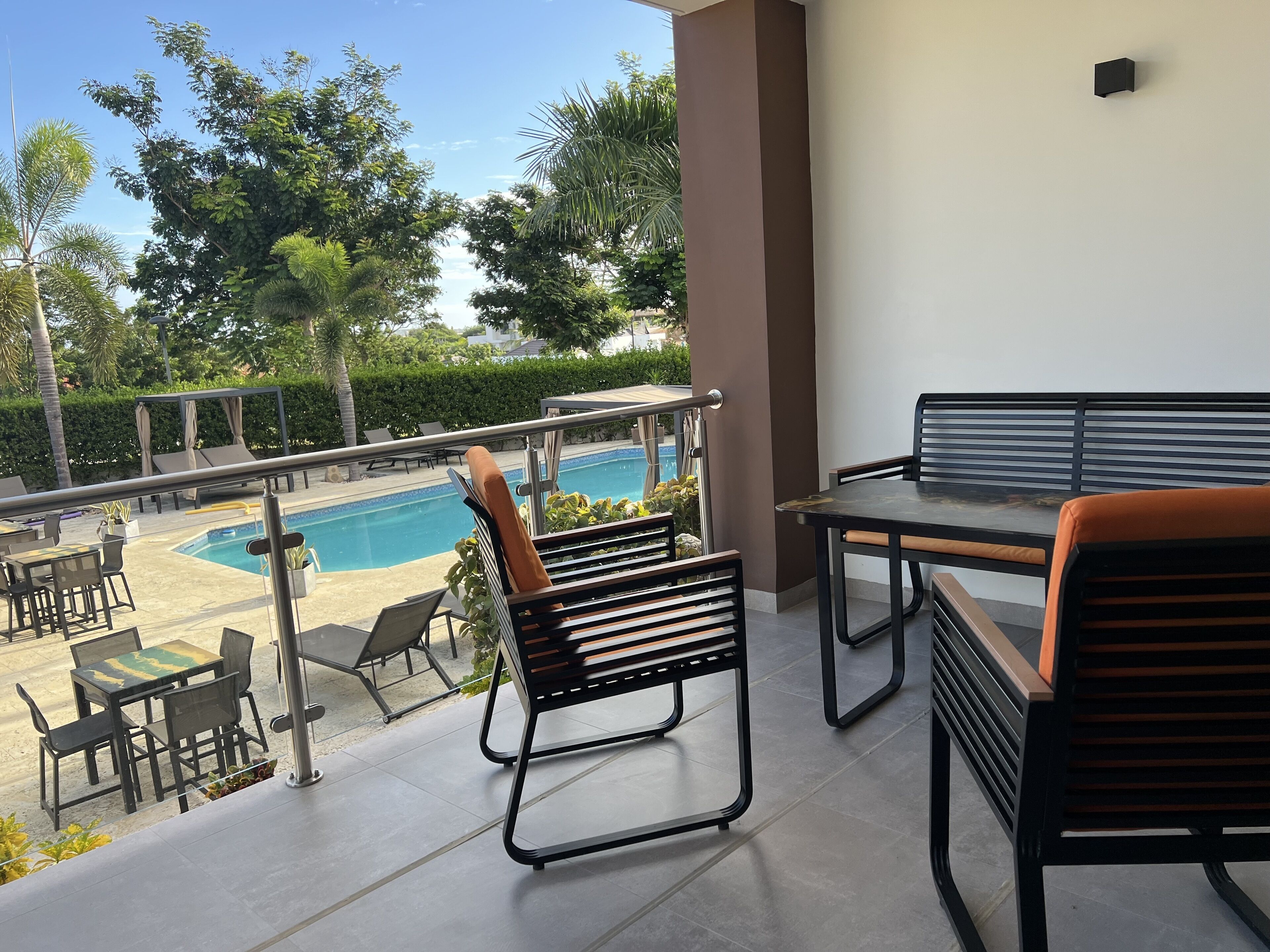 A balcony with a pool view, outdoor seating, and a table.