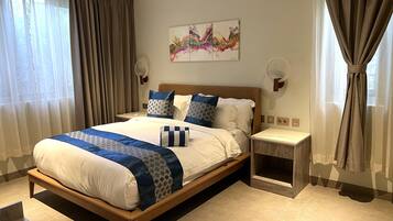 Een hotelkamer met een groot bed, een nachtkastje en een kunstwerk aan de muur.