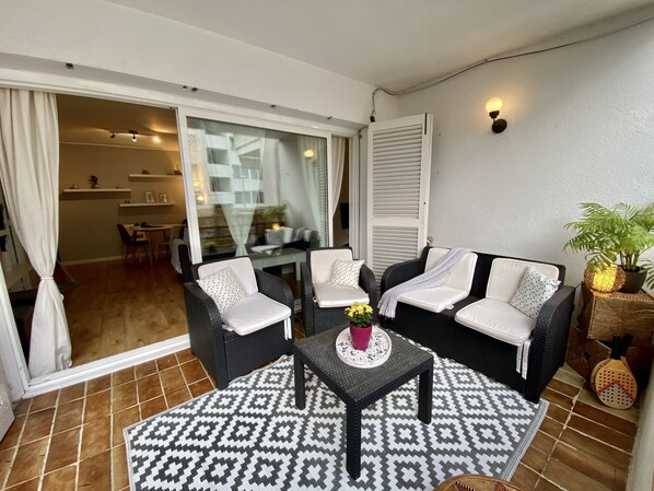 A balcony with a sofa set, a small table, and a potted plant.