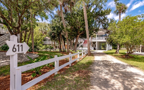 A gated entrance with a sign reading "611" leading to a building with a porch and multiple windows.