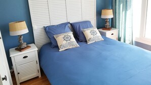 A bed with a blue bedspread and two pillows, a white headboard, two bedside tables with lamps, and a window with curtains. - Superb sea view, 5 minutes from the beach (Criel-sur-Mer)