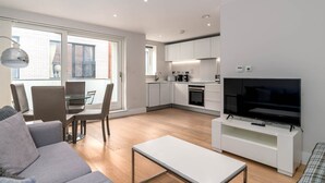 A modern apartment with a dining area, kitchen, and living room.