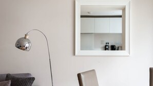 A modern living room with a floor lamp, a framed mirror, and a sofa.