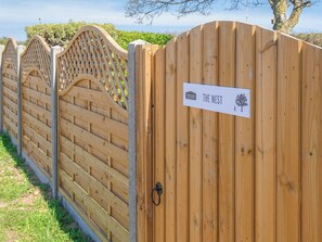A wooden gate with a sign that reads "THE NEST" and a logo for "OUTSIDE ASSEMBLY".