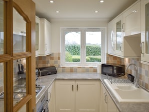 A modern kitchen with a large window, white cabinets, and a built-in microwave.