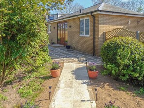 A brick house with a tiled patio, potted plants, and a wooden fence.