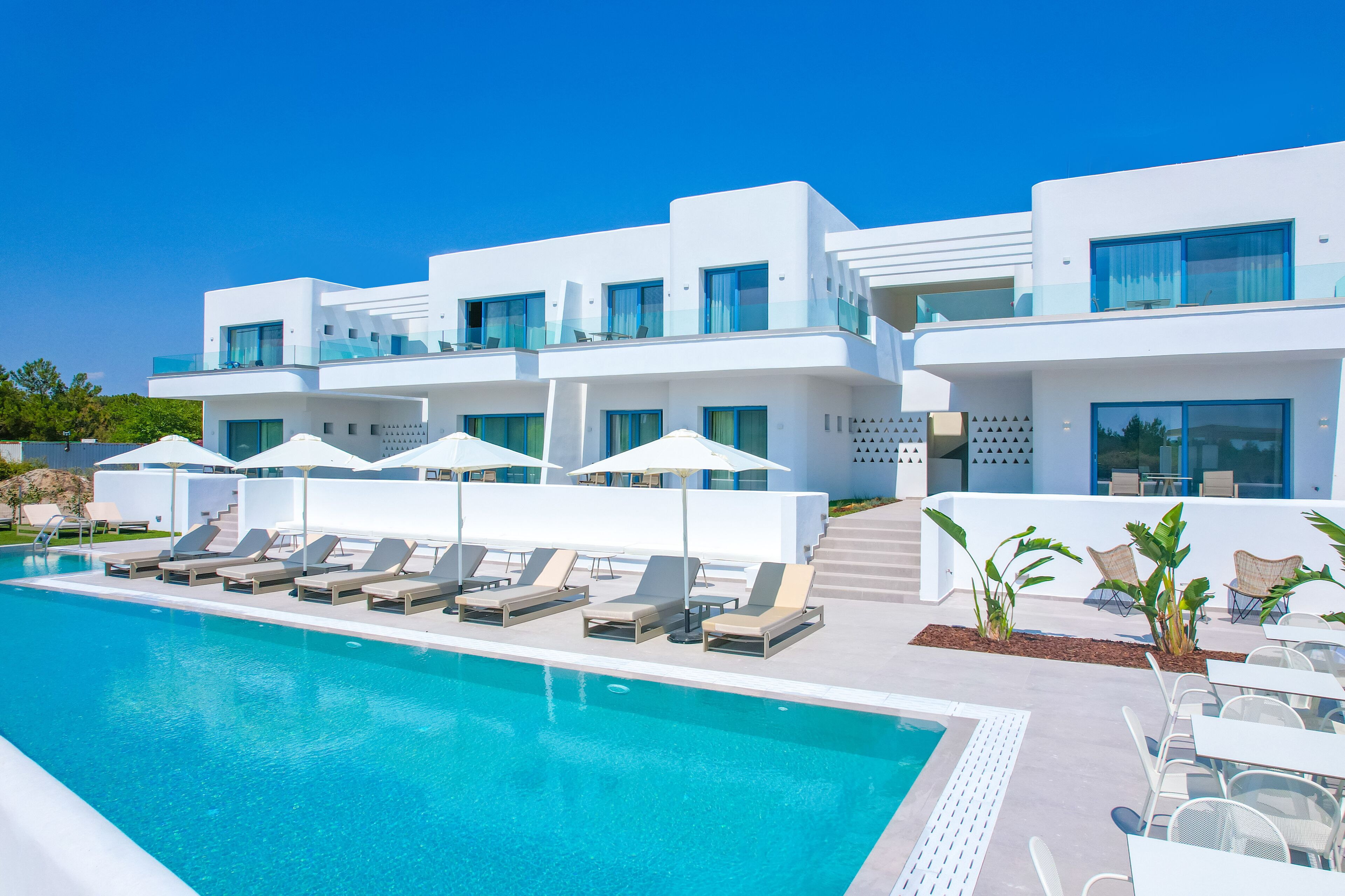 Un hotel moderno con piscina, tumbonas y zona de estar al aire libre.