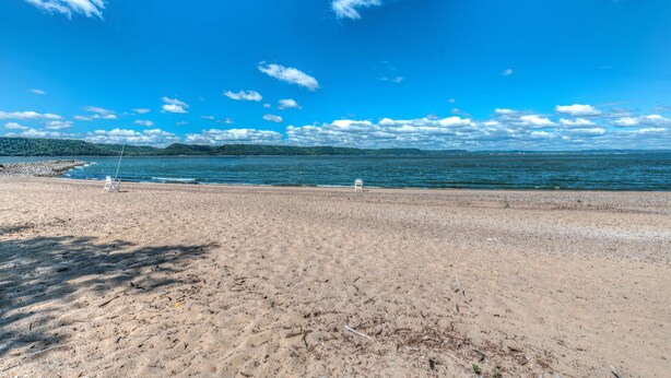 A beach with a clear sky and calm sea. - Studio Condo Near Lake Pepin - King Bed - Dewdrop (Pepin)