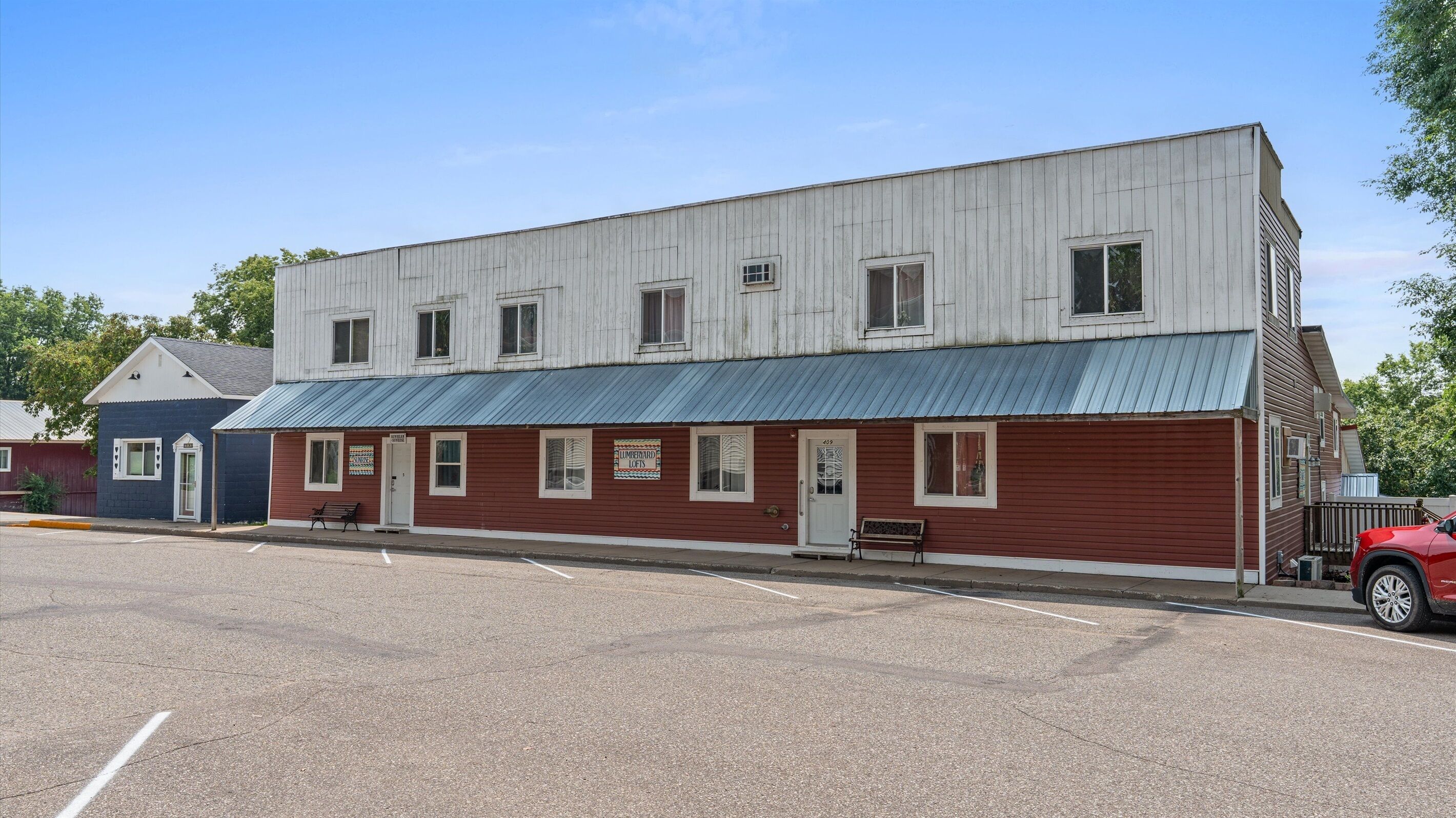 A two-story building with a red and white facade, a blue roof, and a parking lot in front.
