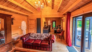 Ein gemütliches Blockhaus-Interieur mit Ledersofa, Holzwänden, einer Chandelier und einem Essbereich.