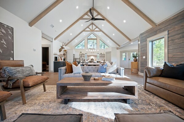 Relax in this inviting living area with a high ceiling, central fan, and comfortable seating.