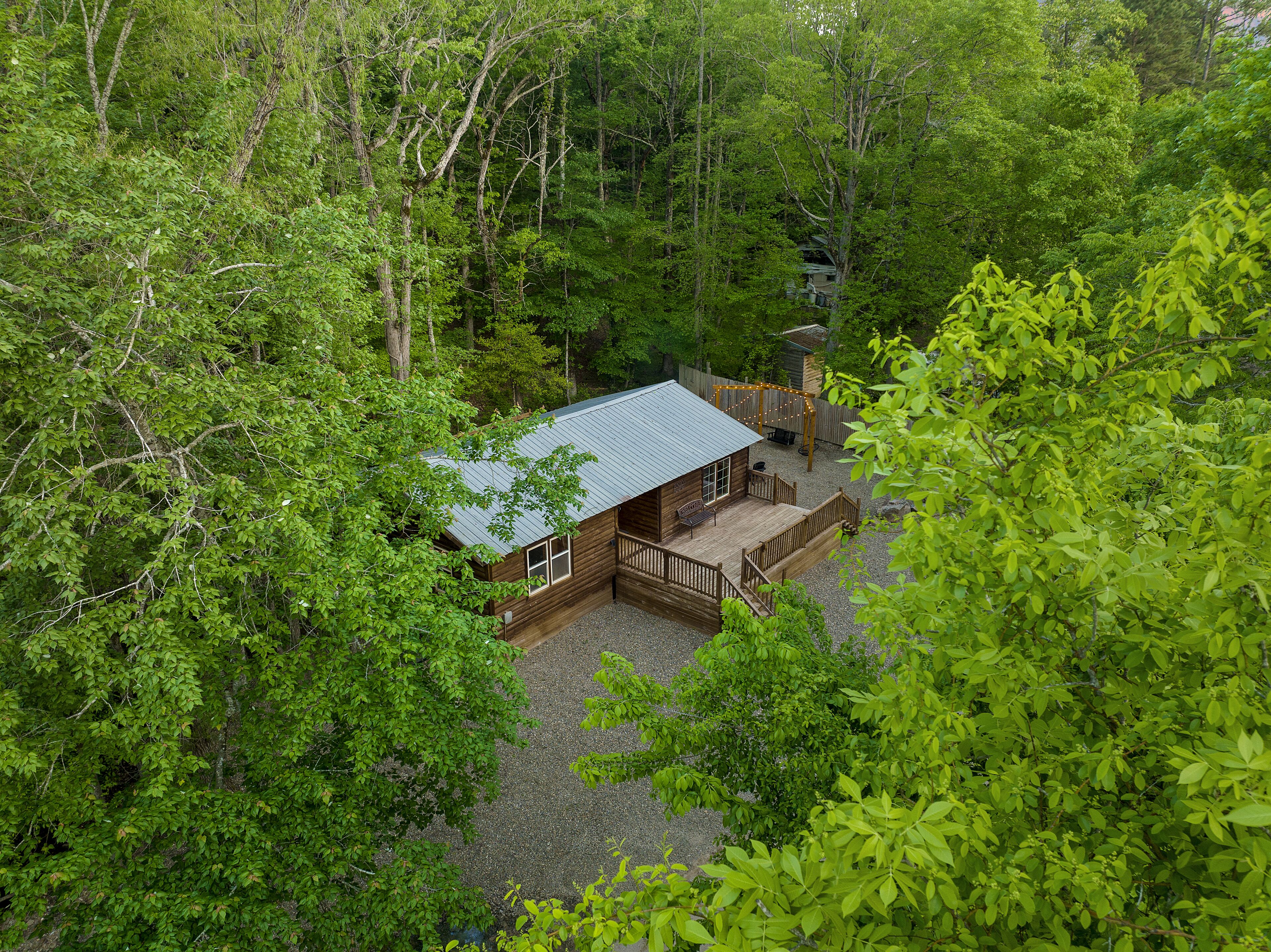 A cabin surrounded by dense forest, with a deck and outdoor seating area.