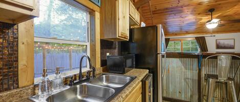 A kitchen with wooden cabinets, a stainless steel sink, a refrigerator, and a microwave.